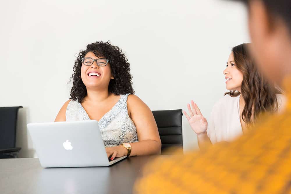 A happy business owner sitting in a meeting with her laptop